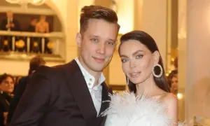 Edyta Zając z partnerem na eleganckim wydarzeniu. Ona w białej kreacji z piórami i błyszczącymi kolczykami, on w garniturze.