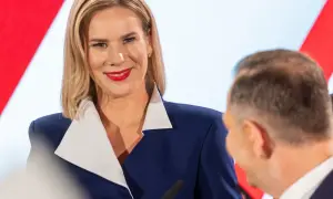 Pierwsza dama Polski, uśmiechnięta, w granatowej marynarce z białym kołnierzem, podczas oficjalnego wydarzenia.