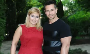 Kobieta w czerwonej sukience i mężczyzna w czarnej koszulce stoją obok siebie na tle zieleni.