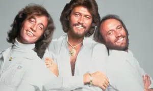 Trzej bracia z Bee Gees, Barry, Robin i Maurice Gibb, uśmiechają się do zdjęcia. Kto żyje? Barry i Robin.
