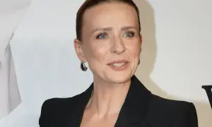 Aneta Zając w czarnej marynarce, z dużymi kolczykami, uśmiecha się. Jej partner, jeśli jest obecny, nie jest widoczny.