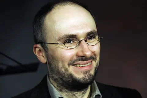 Uśmiechnięty mężczyzna w okularach, z zarostem. Sebastian Krajewski, którego życie prywatne budzi zainteresowanie, wygląda na zrelaksowanego.