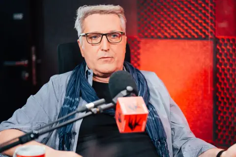 Robert Bernatowicz w studio radiowym, w tle czerwone panele akustyczne. Mówi o swojej żonie.