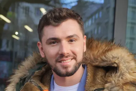 Uśmiechnięty Kamil Bednarek w futrzanej kurtce. Może właśnie wraca do swojej żony po koncercie.
