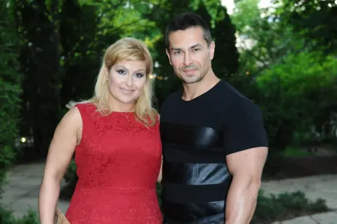 Kobieta w czerwonej sukience i mężczyzna w czarnej koszulce stoją obok siebie na tle zieleni.