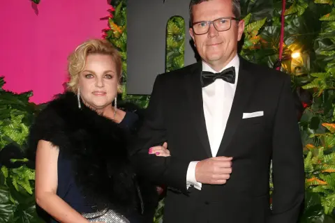 Marcin Bosacki i jego partnerka na ściance. Elegancka para, ona w futrze i biżuterii, on w smokingu.