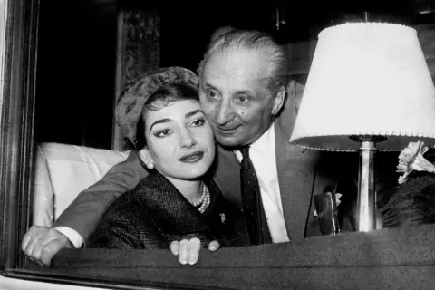 Maria Callas i Giovanni Battista Meneghini, uśmiechnięci, w bliskim uścisku.
