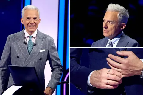 Hubert Urbański w eleganckim garniturze, z widocznym tatuażem na dłoni.