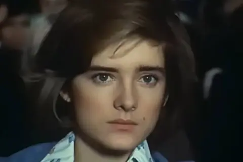Małgorzata Snopkiewicz dzisiaj, młoda dziewczyna z krótkimi włosami i przenikliwym spojrzeniem, w niebieskiej marynarce.
