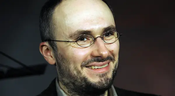 Uśmiechnięty mężczyzna w okularach, z zarostem. Sebastian Krajewski, którego życie prywatne budzi zainteresowanie, wygląda na zrelaksowanego.