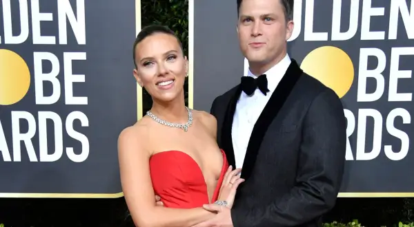 Scarlett Johansson w czerwonej sukni i Colin Jost w garniturze na ściance Golden Globe Awards.