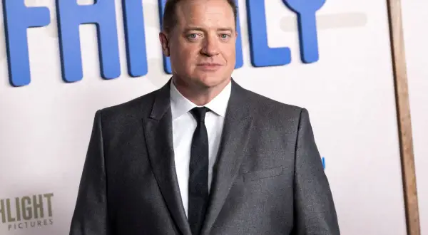Brendan Fraser w garniturze, z widocznym napisem "FAMILY" w tle. Aktor pokonał chorobę i wrócił na czerwony dywan.
