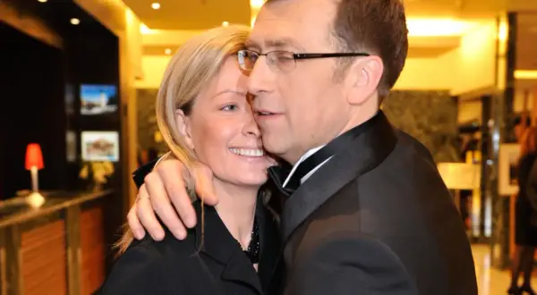 Maciej Orłoś z żoną, uśmiechnięci, w eleganckich strojach, w intymnym uścisku.
