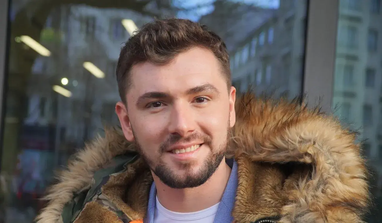 Uśmiechnięty Kamil Bednarek w futrzanej kurtce. Może właśnie wraca do swojej żony po koncercie.