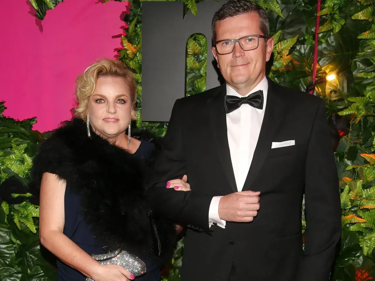 Marcin Bosacki i jego partnerka na ściance. Elegancka para, ona w futrze i biżuterii, on w smokingu.