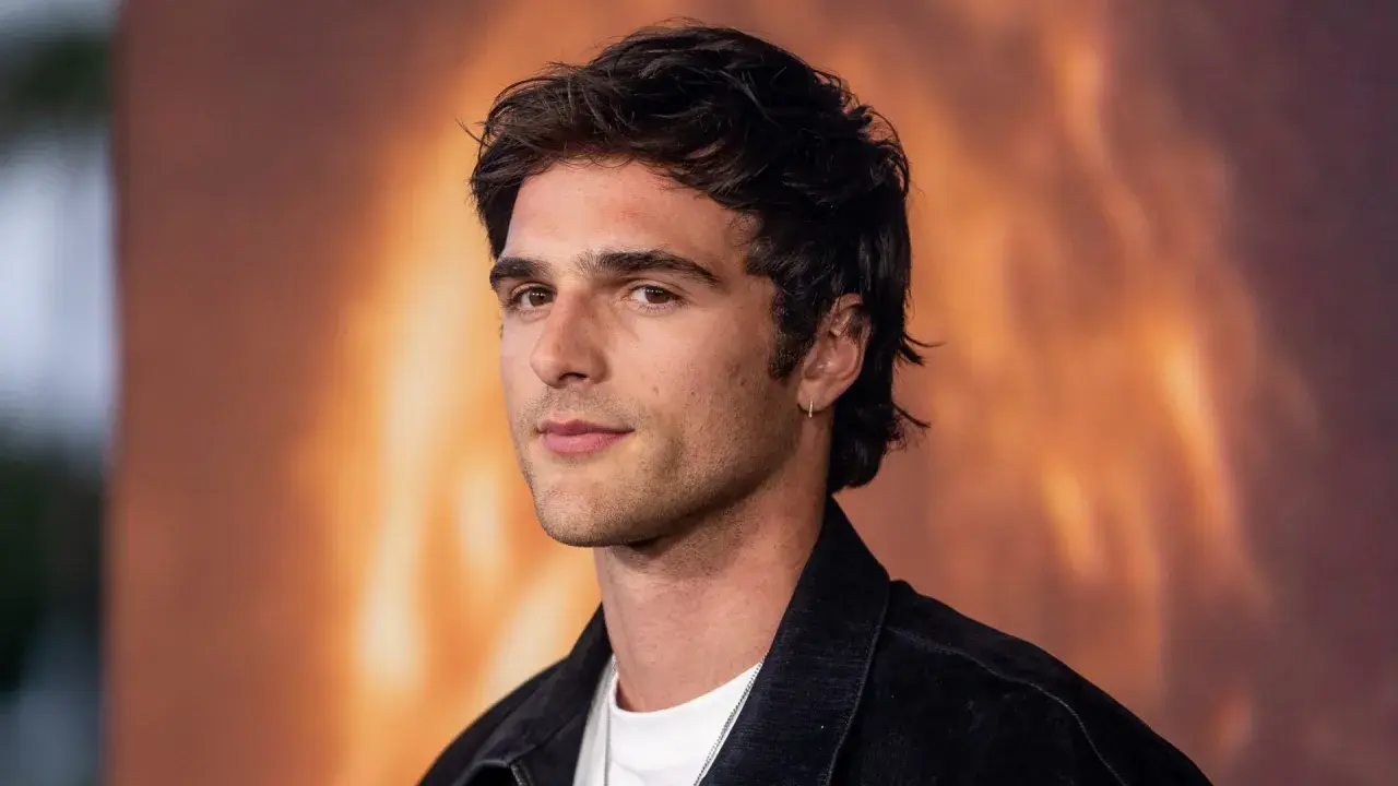 Jacob Elordi, którego dziewczyna może być zazdrosna o jego urok, pozuje na tle ognistego krajobrazu.