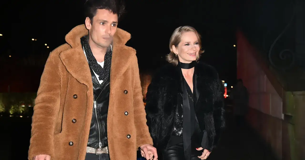 Magdalena Cielecka i Bartosz Gelner spacerują nocą, trzymając się za ręce. Ona w czarnym futrze, on w brązowym płaszczu.