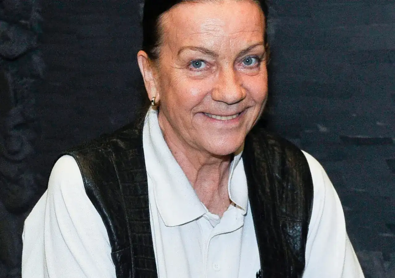 Uśmiechnięta Barbara Burska w białej koszuli i czarnej kamizelce. Jej mężowie to temat, który zawsze budzi zainteresowanie.