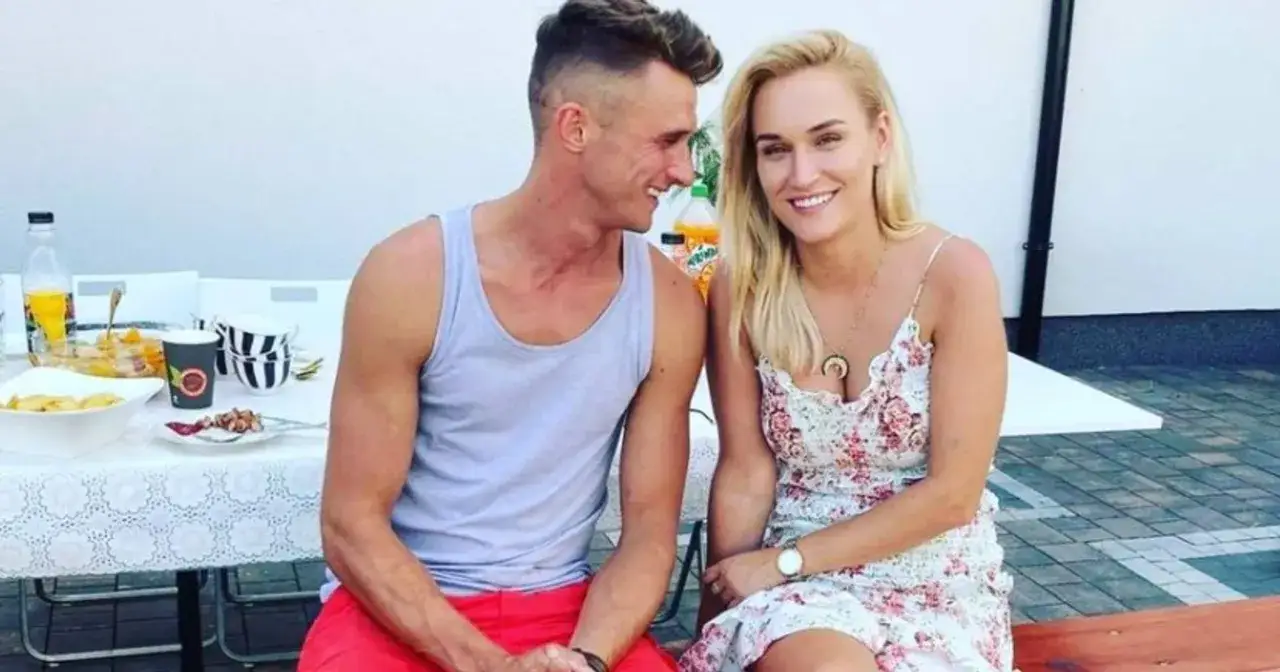 Uśmiechnięta Kamila Boś i jej partner siedzą przy stole z jedzeniem.