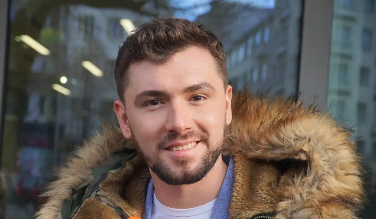 Uśmiechnięty Kamil Bednarek w futrzanej kurtce. Może właśnie wraca do swojej żony po koncercie.