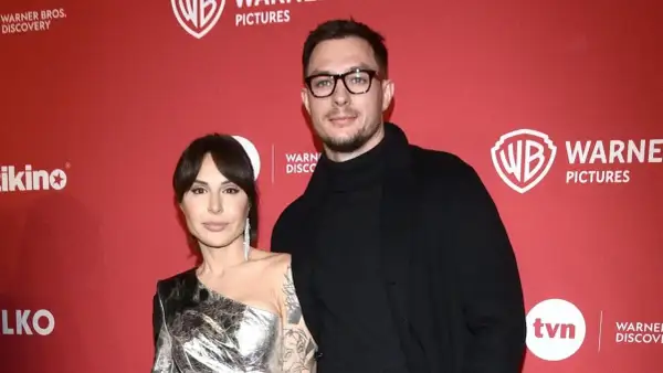 Blanka Lipińska z partnerem na czerwonym tle z logo Warner Bros. Pictures.
