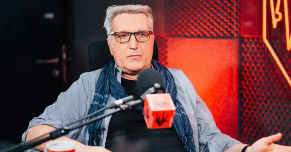 Robert Bernatowicz w studio radiowym, w tle czerwone panele akustyczne. Mówi o swojej żonie.