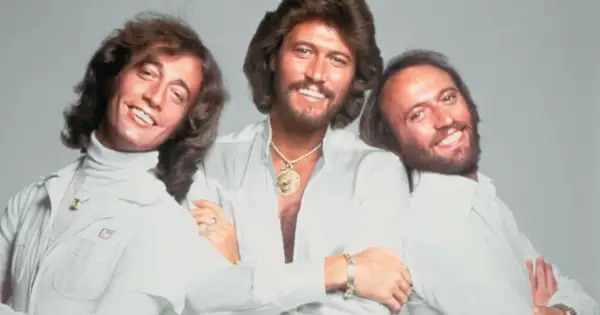 Trzej bracia z Bee Gees, Barry, Robin i Maurice Gibb, uśmiechają się do zdjęcia. Kto żyje? Barry i Robin.