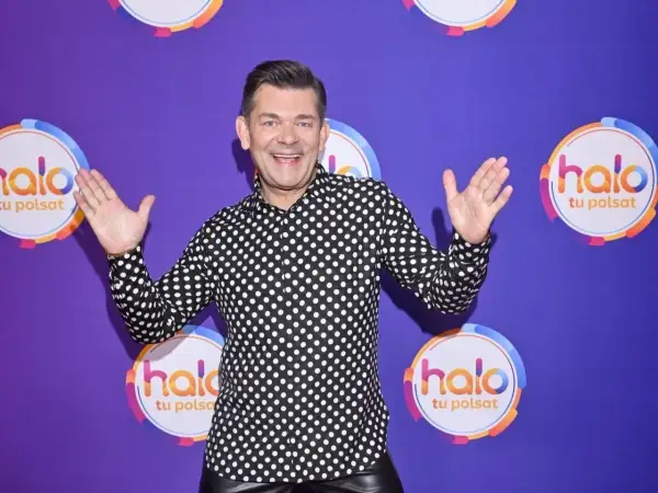 Zenek Martyniuk w czarno-białej koszuli w grochy, z podniesionymi rękami, na tle fioletowym z logo "halo tu Polsat".