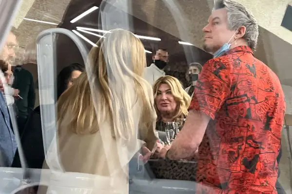 Jakub Łuczak, partner Beaty Kozidrak, w czerwonej koszuli z komiksowym wzorem, rozmawia z kobietą o blond włosach.
