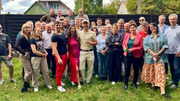 Uśmiechnięta obsada serialu "Barwy szczęścia" 2025 pozuje do wspólnego zdjęcia na trawie.