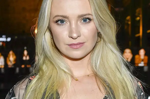 Blondynka z niebieskimi oczami, w złotych kolczykach, wygląda jakby była w centrum uwagi, może nawet w związku z jakąś aferą, jak kurdej szatan afera.